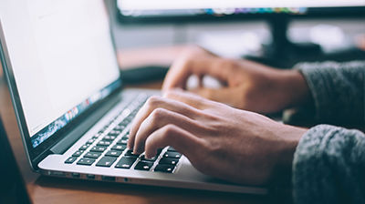 Ivans Download Close up of hands typing on laptop keyboard.